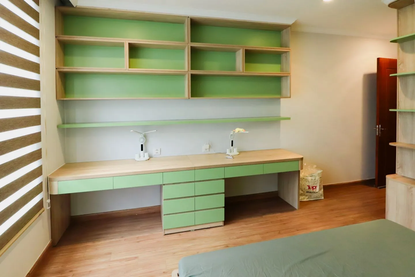 Green desk and matching shelves in a bright home office