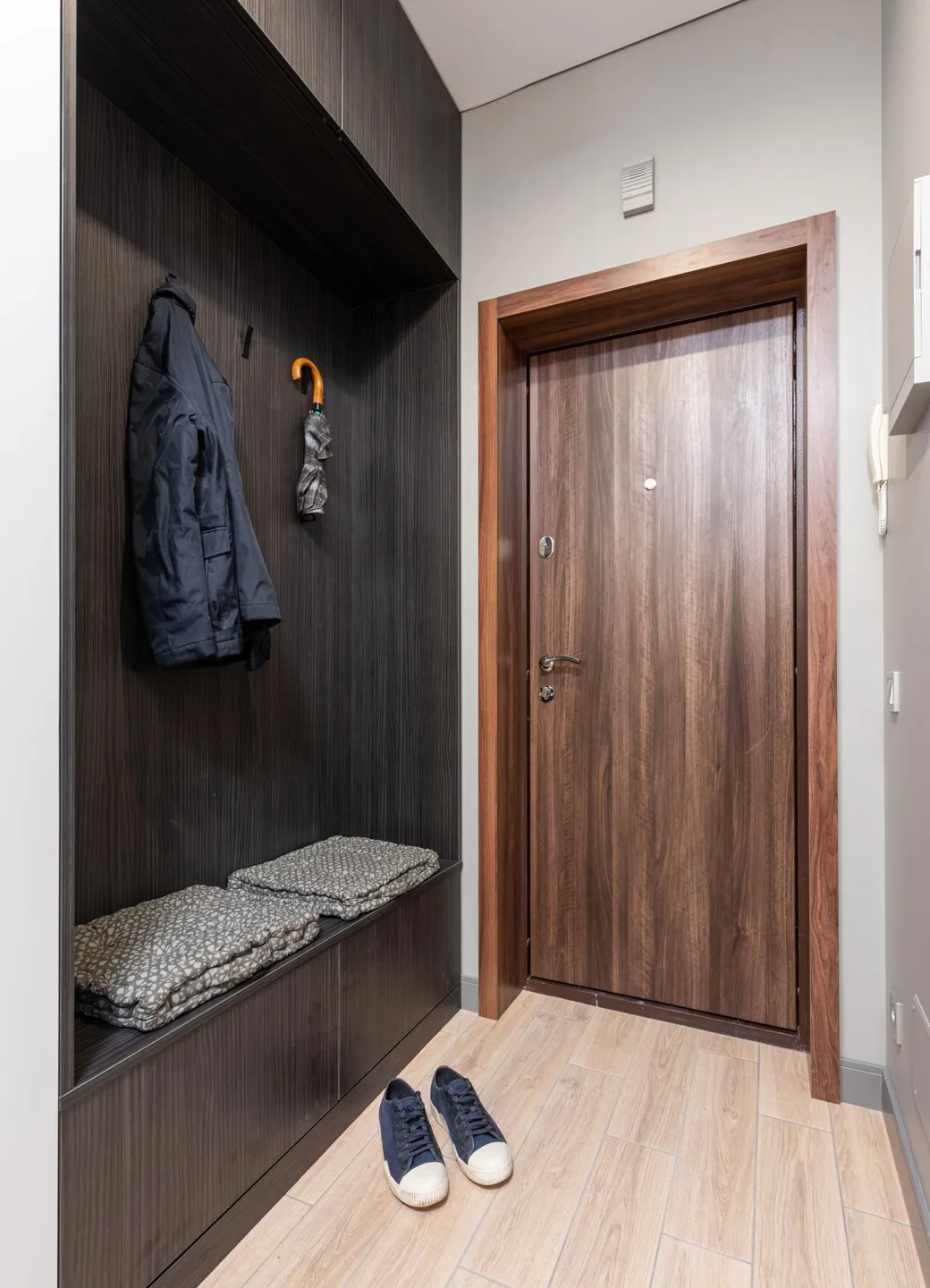 Entryway with wall hooks, a bench, an umbrella and shoes