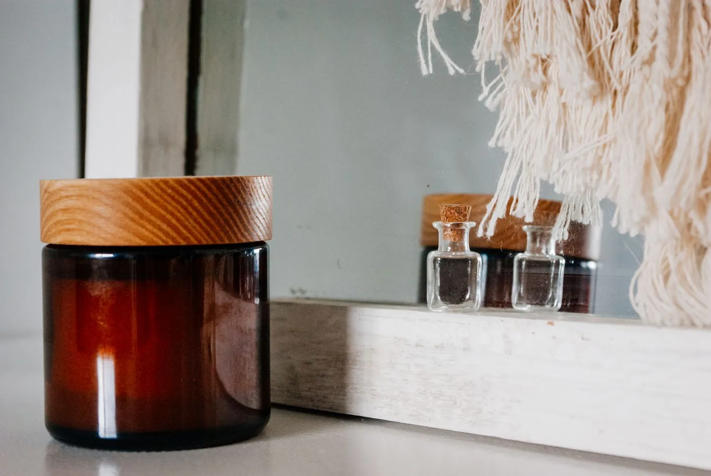 Skincare jar and small bottle beside a dressing mirror