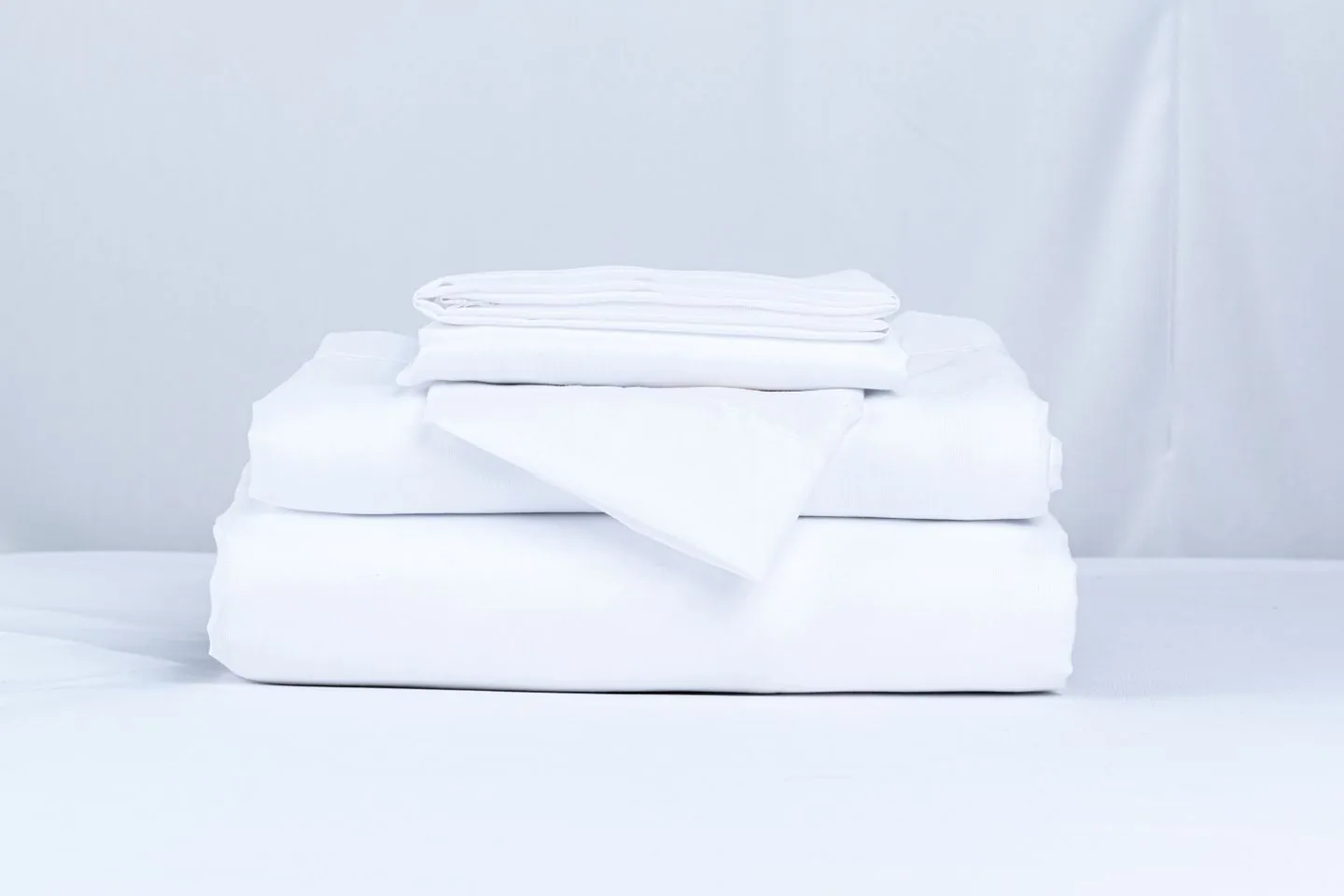 Neatly folded white bed linen stacked together