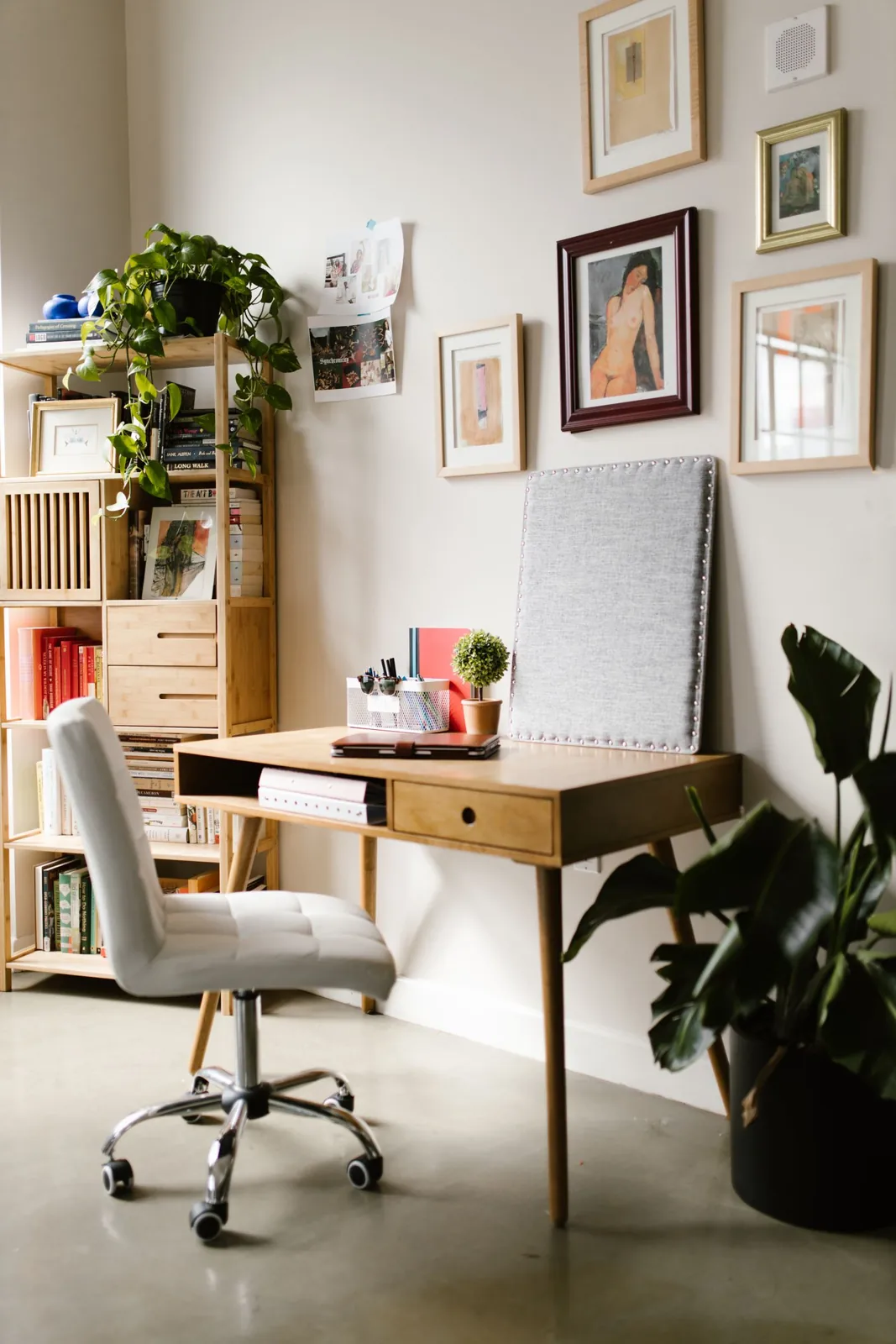Home-office desk beneath a grouping of framed pictures